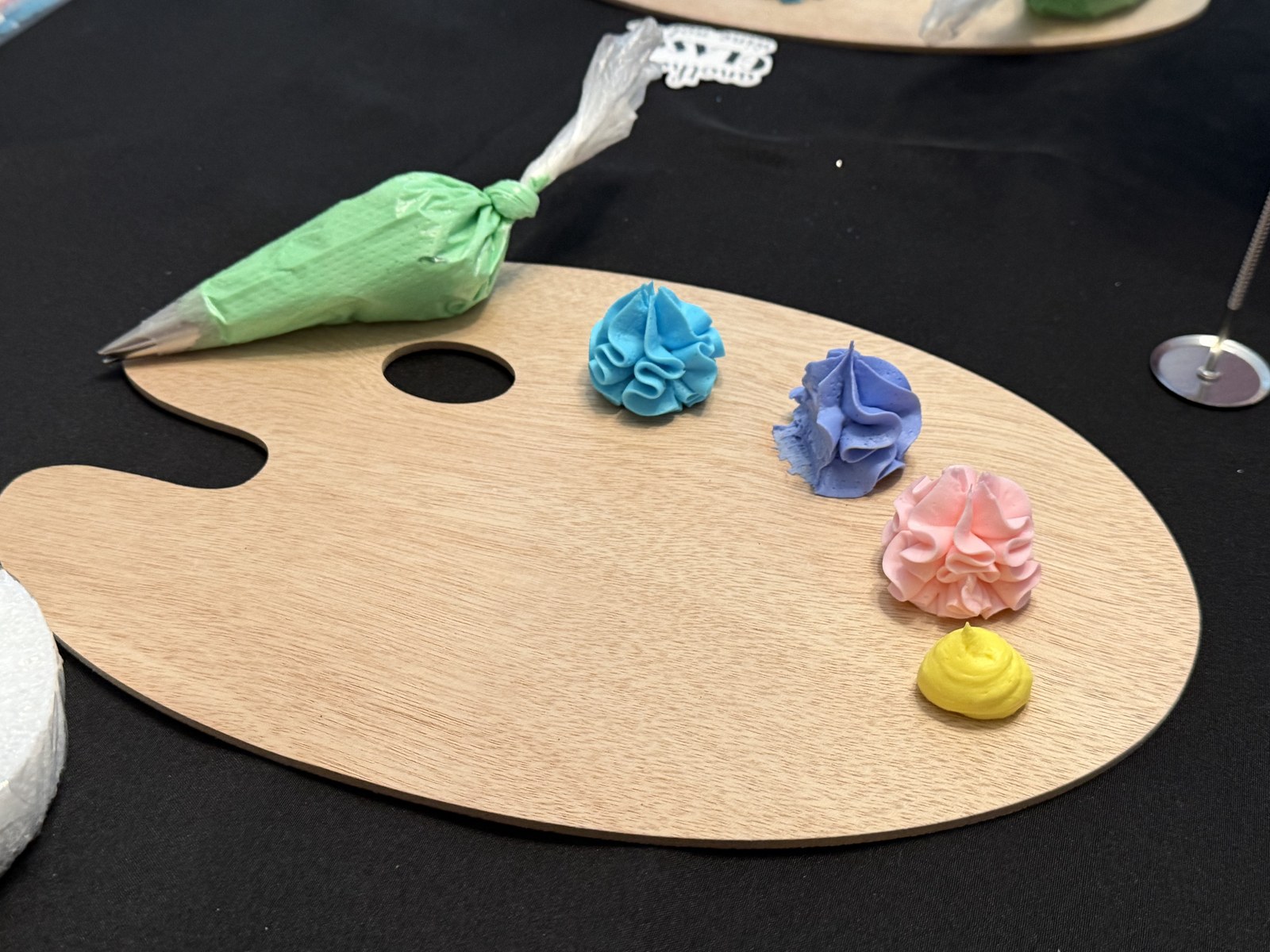 Artist palette with piped frosting colors and green piping bag